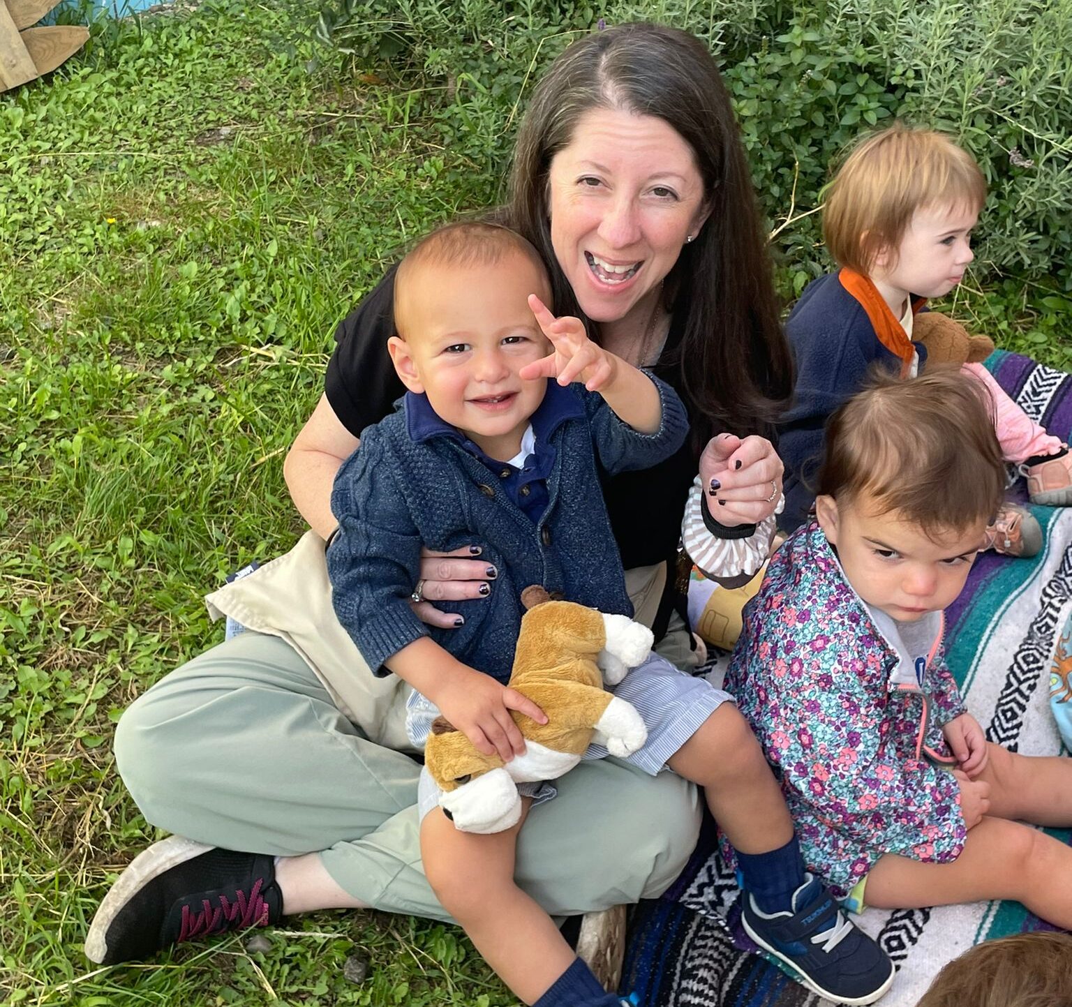 Shalom Yeladim children with their teacher on a picnic blanket.