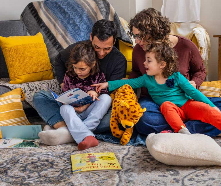 Family with two young children reading a book from the PJ Library.